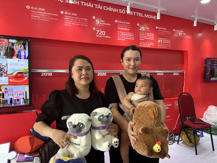 Mẹ con chị Tuyết Mai (quận 1) cùng với bạn ôm gấu bông, quà tặng tại gian hàng Viettel Money trong Lễ hội Không tiền mặt 2024 - Ảnh: THẢO THƯƠNG