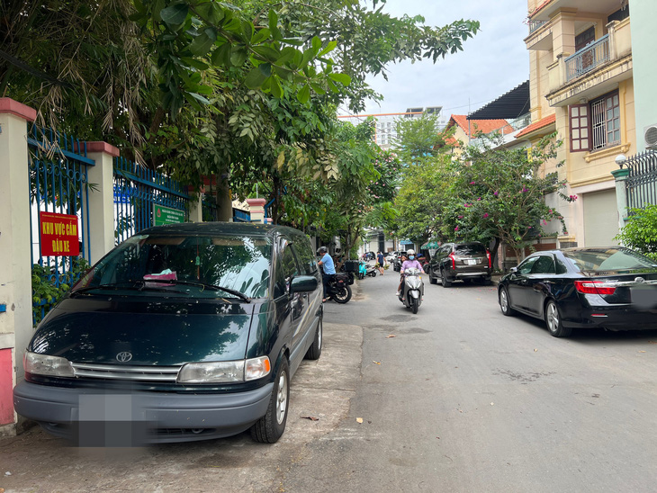 Biển "khu vực cấm đậu xe" treo trên tường rào của ủy ban phường nhưng ô tô vẫn đậu - Ảnh: XUÂN ĐOÀN