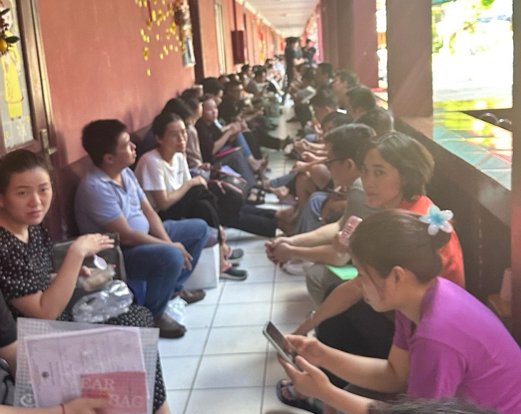Phụ huynh chờ ở ngoài hành lang trường trong sáng 17-6 - Ảnh: PHCC