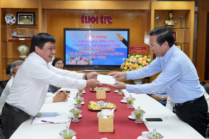 Chủ tịch UBND TP.HCM Phan Văn Mãi trao quà chúc mừng báo Tuổi Trẻ đến Tổng biên tập Lê Thế Chữ - Ảnh: HỮU HẠNH 