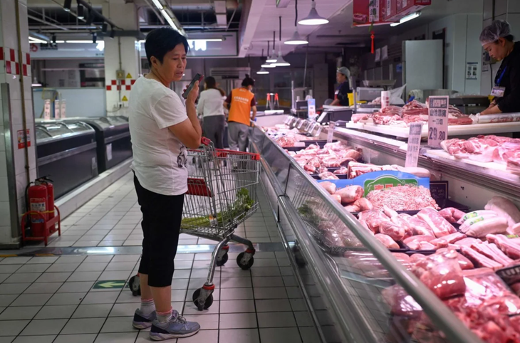 Một người tiêu dùng trước quầy thịt heo tại một siêu thị ở Trung Quốc - Ảnh: AFP