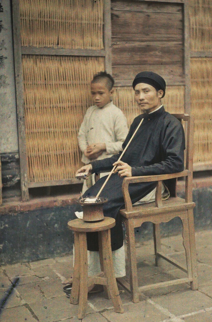 Ông lý trưởng hút thuốc lào trên sân nhà - Ảnh: Léon Busy