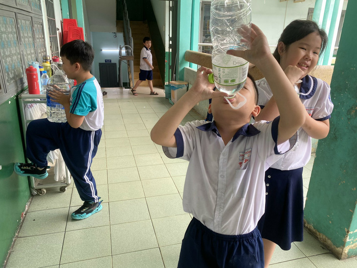 Bên trong trường, nhiều học sinh khi ra chơi phải bê những bình nước lớn để tự lấy nước uống - Ảnh: PHCC