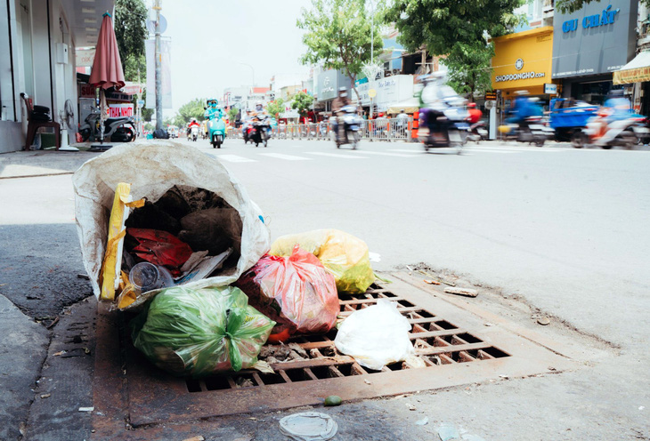 Người dân vứt rác ngay trên miệng cống thoát nước trên đường Quang Trung, quận Gò Vấp - Ảnh: THANH HIỆP