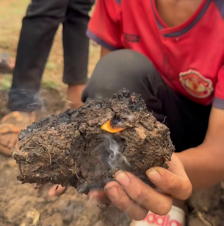 Người dân nâng một cục đất đang cháy tại cánh đồng xã Bar Măih - Ảnh: Minh Nam 