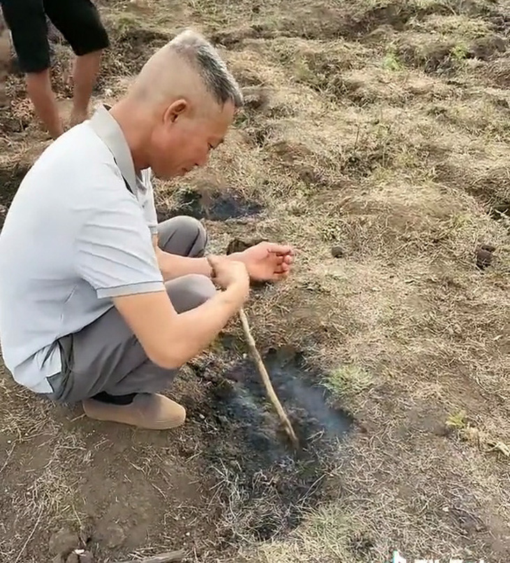 Người đàn ông dùng que chọt xuống mô đất đang bốc khói trên cánh đồng xã Bar Măih, huyện Chư Sê, Gia Lai - Ảnh: TikTok 