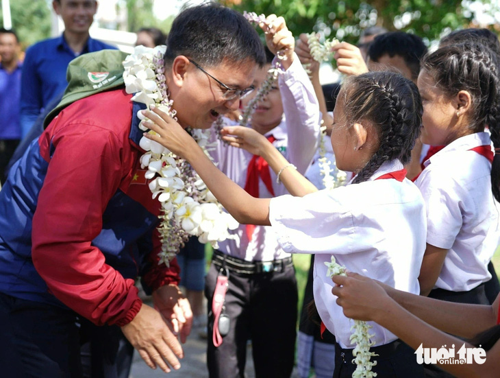 Học sinh Trường tiểu học Kilomet số 3 (tỉnh Attapeu, Lào) đeo vòng hoa cho Trưởng Ban Dân vận Thành ủy TP.HCM Nguyễn Mạnh Cường - Ảnh: DIỆU QUÍ