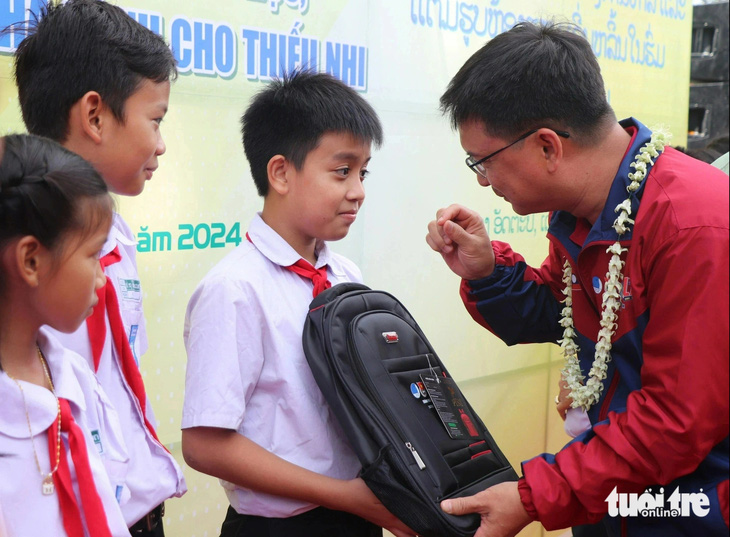 Ông Nguyễn Mạnh Cường - trưởng Ban Dân vận Thành ủy TP.HCM - trao ba lô cho học sinh Lào - Ảnh: DIỆU QUÍ