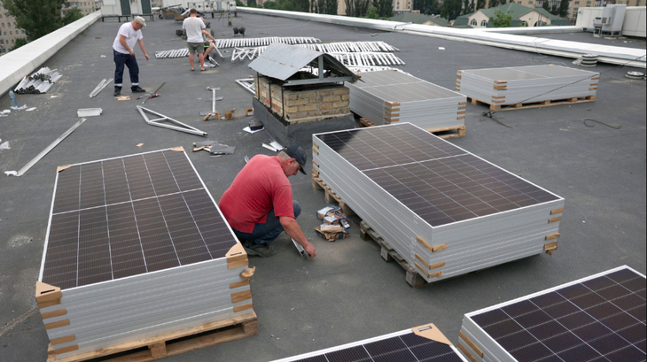Các nhân viên lắp tấm pin mặt trời trên mái nhà trong thời gian mất điện một phần ở Kiev hôm 14-6, sau cuộc tấn công của Nga vào cơ sở hạ tầng năng lượng của Ukraine - Ảnh: AFP