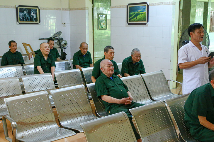 Y sĩ Lê Quang Đoan (bìa phải) và các thương binh theo dõi tin tức trên tivi tại khoa điều trị 1, Trung tâm điều dưỡng thương binh Kim Bảng, Hà Nam - Ảnh: HÀ QUÂN