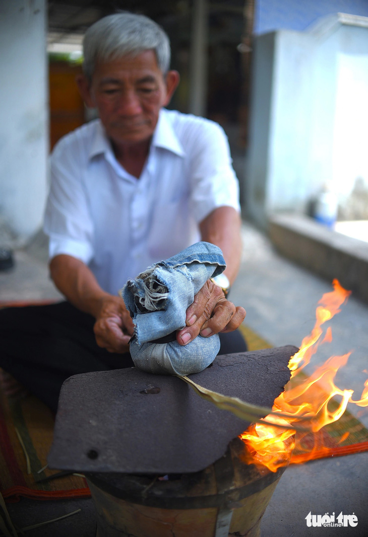 Nghệ nhân Đặng Văn Lan dùng lửa và tấm vải dày vuốt thẳng những sợi lá kè đã phơi khô để chuẩn bị làm nón ngựa