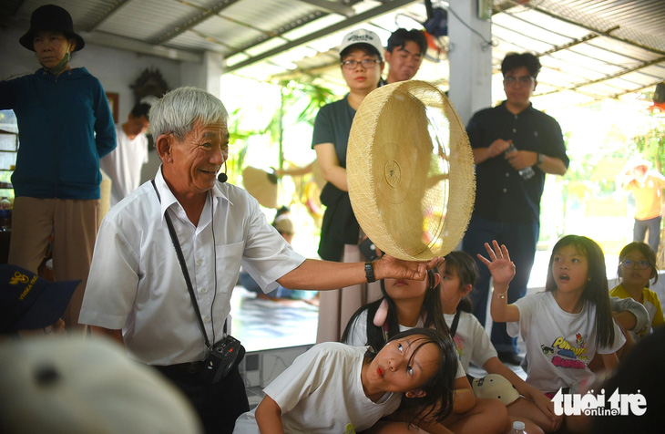 Nghệ nhân Đặng Văn Lan giới thiệu các công đoạn để làm nên một chiếc nón ngựa Phú Gia với các học sinh
