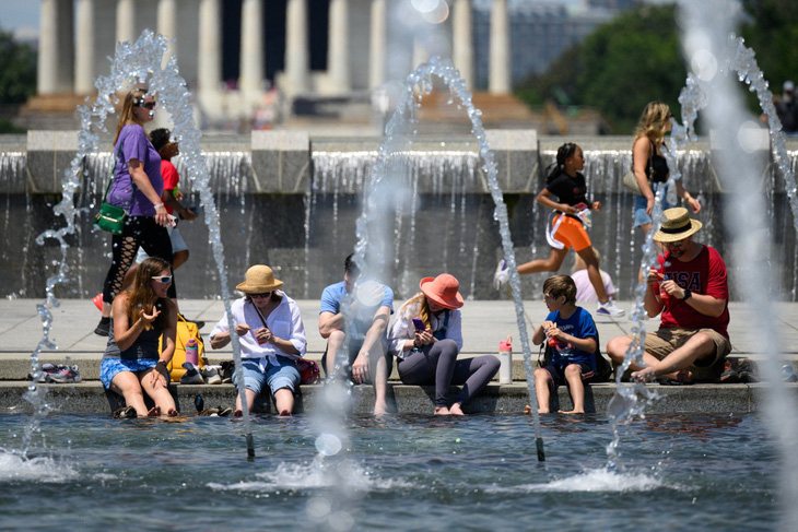 Mọi người ngâm chân vào nước giữa cái nóng tại Đài tưởng niệm Thế chiến 2 ở Washington D.C hôm 19-6 - Ảnh: AFP