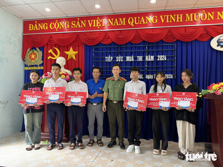Thiếu tá Trương Văn Quốc - trưởng Ban thanh niên Công an tỉnh Kiên Giang - trao học bổng tiếp sức cho các em thí sinh có hoàn cảnh khó khăn ở xã Hòn Tre (huyện Kiên Hải) đi thi - Ảnh: CHÍ CÔNG