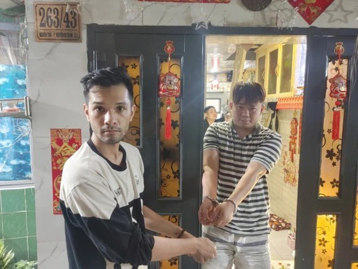 Nam người mẫu Đinh Nhi Ko Lai (bên trái) thực hiện lại hành vi mua ma túy - Ảnh: CACC