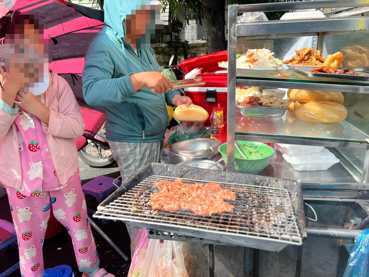 Xe bánh mì ở Khu chế xuất Tân Thuận (quận 7) nướng thịt trên vỉ nướng đã ám đầy dầu mỡ và thịt khét đóng thành lớp - Ảnh: AN VI