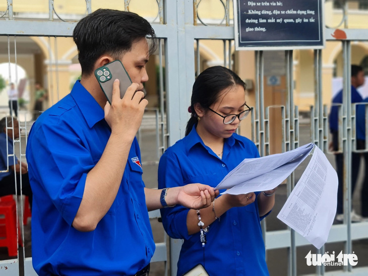 Các tình nguyện viên tại một điểm thi ở Tiền Giang gọi điện cho một phụ huynh khi sắp đến giờ thi mà chưa thấy thí sinh - Ảnh: MẬU TRƯỜNG