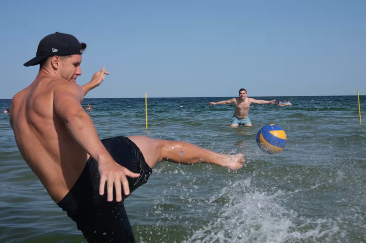 Hai thanh niên người Ukraine hào hứng chơi bóng đá tại Biển Đen trước cơ hội của Ukraine tại mùa giải Euro 2024. Những bãi biển tại khu vực Odessa thường nhộn nhịp vào mỗi dịp cuối tuần, sau khi chính quyền xác nhận các mối đe dọa từ mìn đã giảm đáng kể - Ảnh: RICHARD MORGAN
