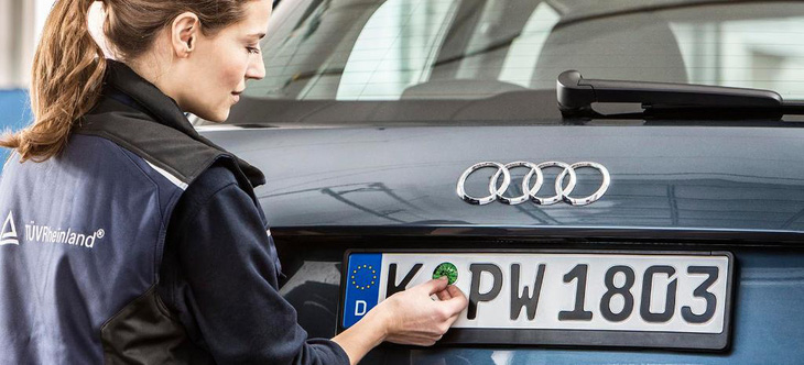 Tại Đức, tem chứng nhận kiểm tra khí thải định kỳ được dán trên biển số ô tô - Ảnh: TÜV
