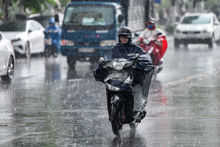 Người dân Hà Nội di chuyển trên đường Lê Văn Lương trong cơn mưa dông chiều 4-6 - Ảnh: NAM TRẦN