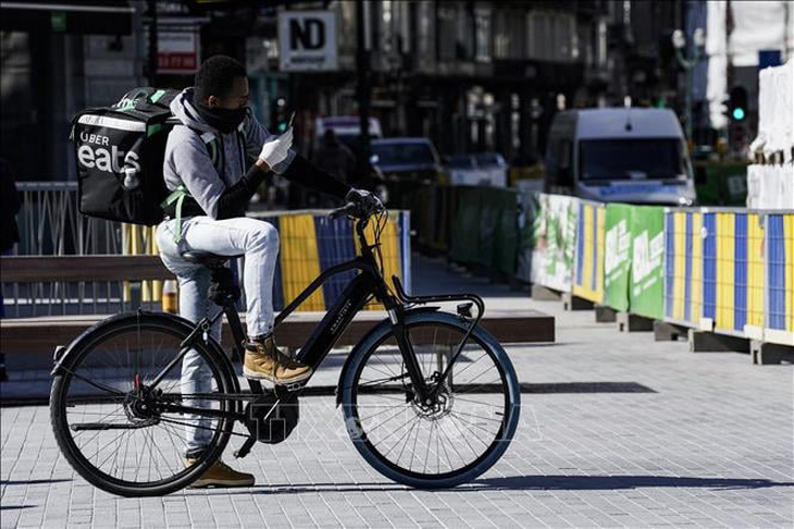 Nhân viên giao hàng di chuyển bằng xe đạp trên đường phố tại Brussels, Bỉ - Ảnh: AFP/TTXVN