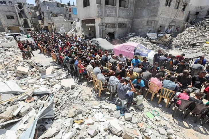 Rất đông người Palestine đang ngồi trong bữa ăn do một bếp từ thiện nấu ở gần các ngôi nhà đã bị hỏa lực của quân đội Israel phá hủy tại vùng Khan Younis, phía nam Dải Gaza hôm 30-5 - Ảnh: REUTERS