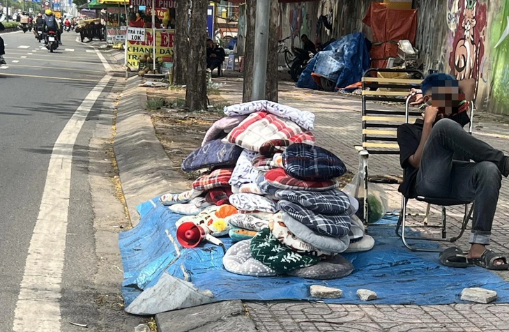 Thanh niên bán gối trên đường Phạm Văn Đồng, đoạn phường 13, quận Bình Thạnh (TP.HCM) ngồi nghỉ ngơi, để cho chiếc loa rao inh ỏi lúc giữa trưa