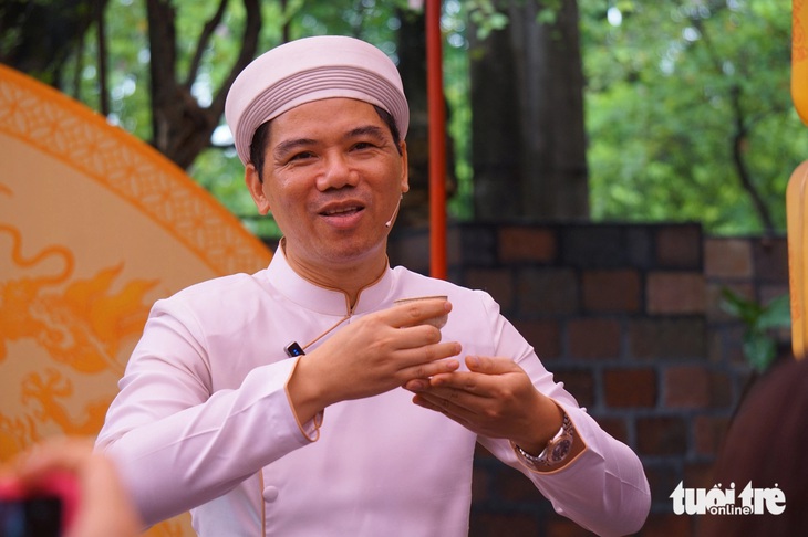 Nghệ nhân trà Hoàng Anh Sướng hướng dẫn cách nâng chén trà mời khách trong buổi nói chuyện về văn hóa thưởng trà tại Hoàng Thành Thăng Long ngày 6-6 - Ảnh: T.ĐIỂU