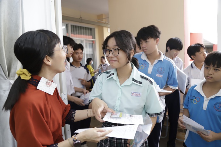 Cán bộ coi thi kiểm tra giấy báo dự thi và giấy tờ cá nhân thí sinh trước khi vào phòng thi môn văn tại điểm thi trường THCS Kim Đồng Q.5, TP.HCM - Ảnh: NHƯ HÙNG