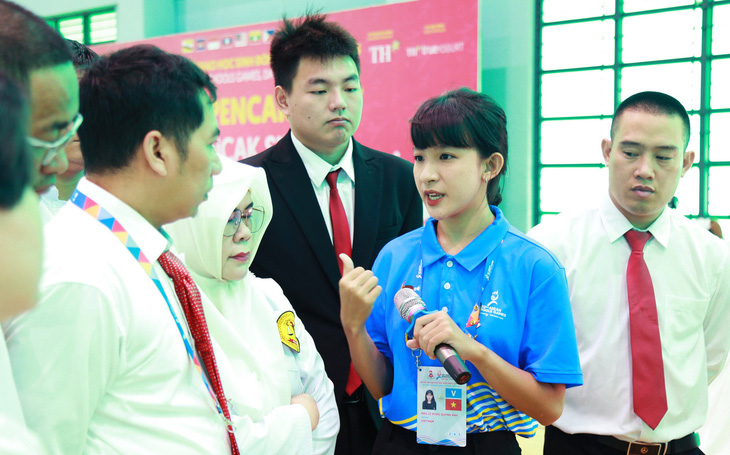 Quỳnh Anh (thứ hai, từ phải qua) phiên dịch cho trưởng đoàn cùng trọng tài tại một trận đấu chung kết pencak silat - Ảnh: ĐOÀN NHẠN