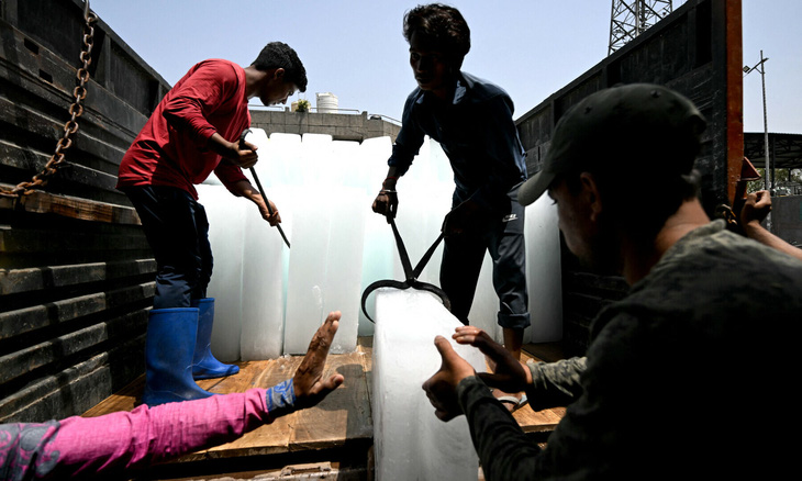 Công nhân khuân nước đá tại một khu chợ ở New Delhi, Ấn Độ hôm 30-5, trong bối cảnh nắng nóng đang diễn ra - Ảnh: AFP