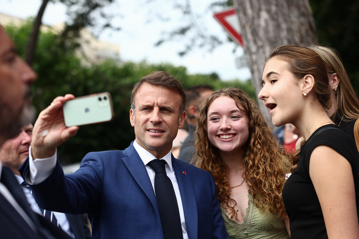 Tổng thống Pháp Emmanuel Macron chụp ảnh với cử tri trẻ ngày 30-6 - Ảnh: REUTERS