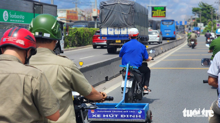 Đoàn thanh niên phường Trung Mỹ Tây (quận 12) phối hợp công an phường triển khai hút đinh trên quốc lộ 1 vào trưa 29-6 - Ảnh: NGỌC KHẢI