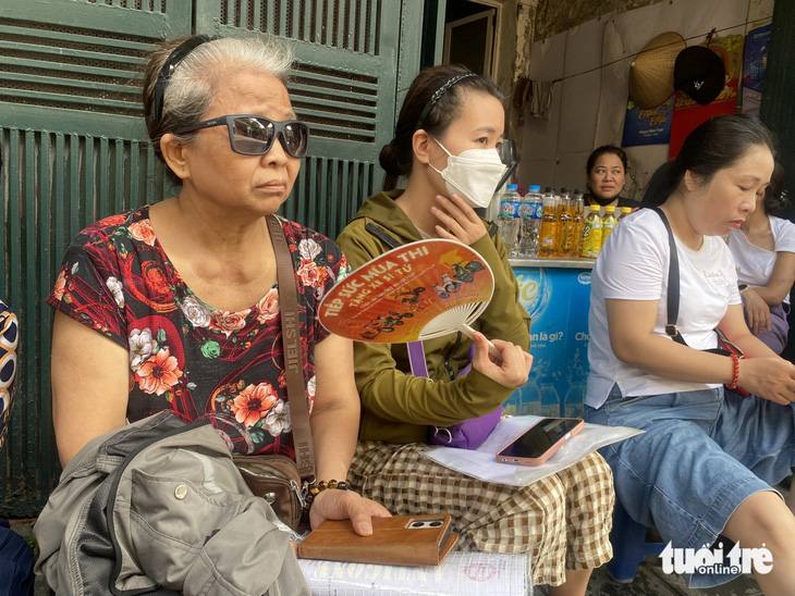 Bà Hoàng Thị Nga (quận Hoàng Mai) cùng nhiều phụ huynh ngồi chờ đợi trường mở cổng để xin vào nộp hồ sơ trực tiếp