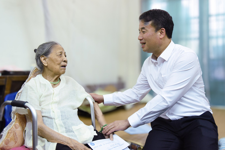 Tổng giám đốc Bảo hiểm xã hội Việt Nam Nguyễn Thế Mạnh chia sẻ niềm vui với một người dân đã hưởng lương hưu mới tại Hà Nội - Ảnh: KHÁNH DUY