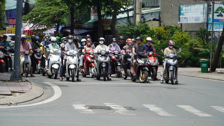 Nhiều người tranh thủ bấm điện thoại khi dừng đèn đỏ ở giao lộ Phạm Văn Đồng - Đào Trinh Nhất, TP Thủ Đức - Ảnh: ĐỊNH DƯƠNG