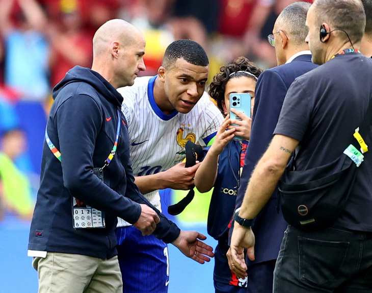 Mbappe vui vẻ chụp hình cùng cậu bé chạy xuống sân sau trận đấu với Bỉ - Ảnh: REUTERS