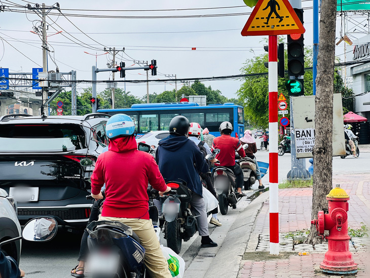 Đèn đỏ cho phép xe máy rẽ phải nhưng người dân đã dừng hết phần đường cho xe rẽ - Ảnh: XUÂN ĐOÀN