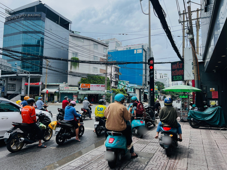 Leo lên vỉa hè tìm cách rẽ phải khi đèn đỏ - Ảnh: XUÂN ĐOÀN