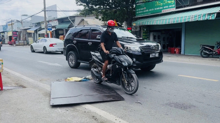 Người đi đường phải nhớm người lên để giữ thăng bằng khi đi qua tấm thép chỏng chơ - Ảnh: XUÂN ĐOÀN