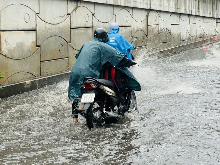 Xe bị chết máy, người dân bì bõm lội nước dắt bộ - Ảnh: XUÂN ĐOÀN