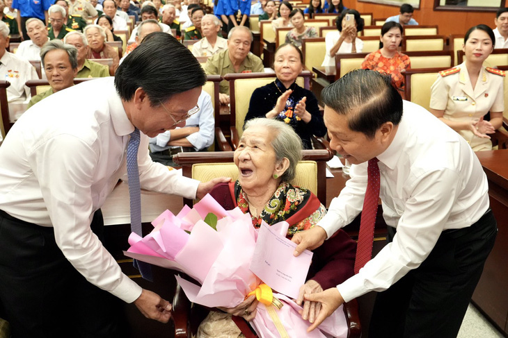 Chủ tịch UBND TP.HCM (trái) và ông Lê Tấn Dũng, thứ trưởng Bộ Lao động - Thương binh và Xã hội, tặng quà cho các Mẹ Việt Nam anh hùng - Ảnh: HỮU HẠNH