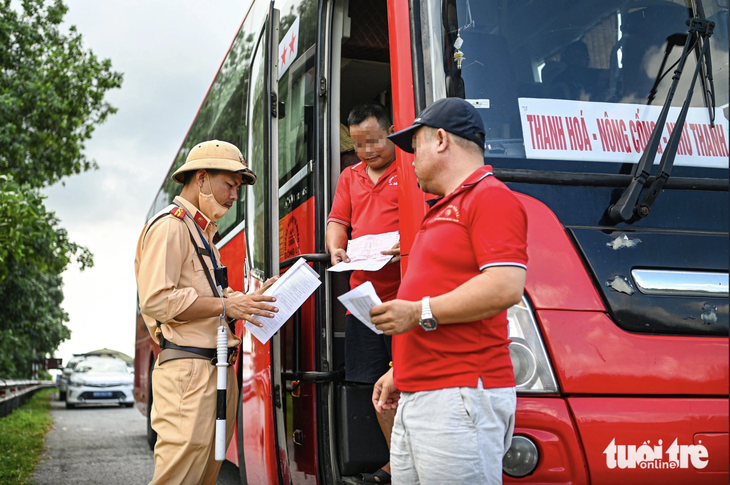 Cảnh sát giao thông kiểm tra giấy tờ của người lái xe - Ảnh: HỒNG QUANG