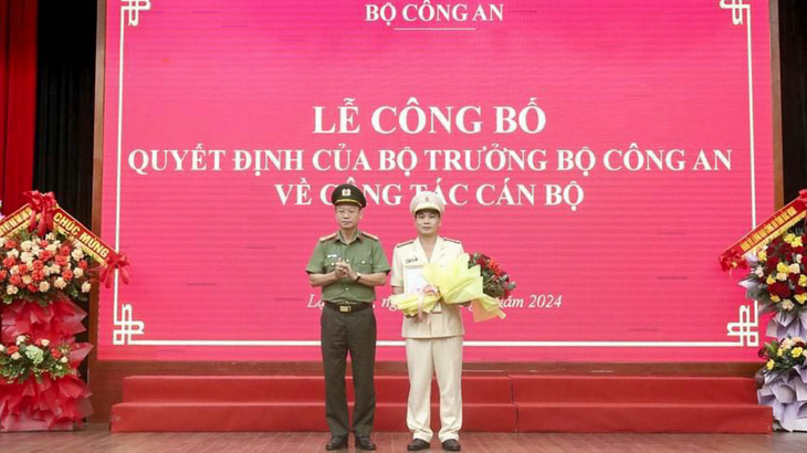 Thừa ủy quyền của bộ trưởng Bộ Công an, đại tá Vũ Như Hà - giám đốc Công an tỉnh Lạng Sơn - trao quyết định và tặng hoa chúc mừng thượng tá Nguyễn Quang Huyên - Ảnh: HOÀNG THƠ