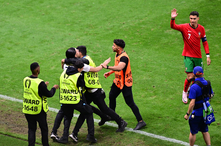 Các nhân viên bảo vệ giữ chặt một người hâm mộ quá khích muốn tiếp cận Ronaldo - Ảnh: Reuters