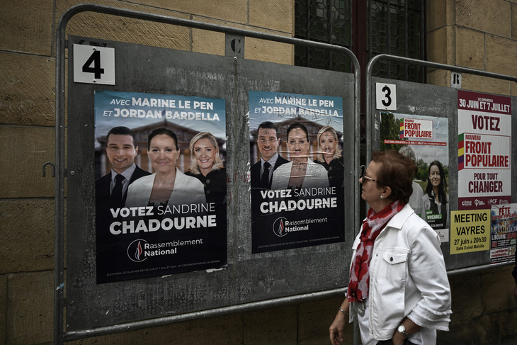 Một cử tri Pháp đứng bên cạnh hình ảnh của các ứng cử viên RN trong chiến dịch bầu cử ngày 2-7 - Ảnh: AFP
