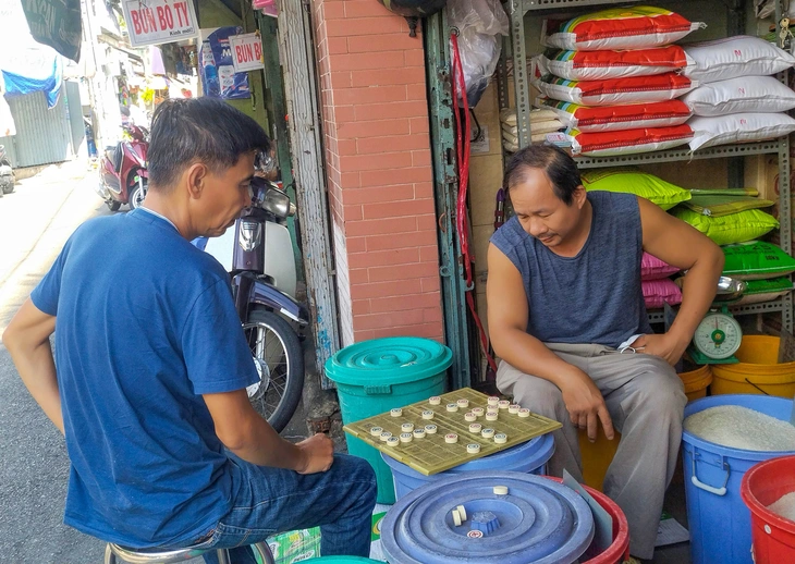 Chú Ngọc Châu và chú Thắng sinh sống và mua bán ở chợ Ga hơn 20 năm, chơi cờ trong khi vắng khách - Ảnh: CẨM HỒNG