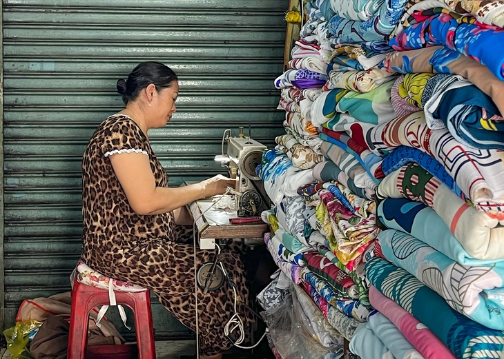 Cô Huệ, một người thợ may vá, sửa đồ có thâm niên hơn 10 năm. Chỉ với góc làm việc vỏn vẹn 2m² - Ảnh: THANH PHƯƠNG