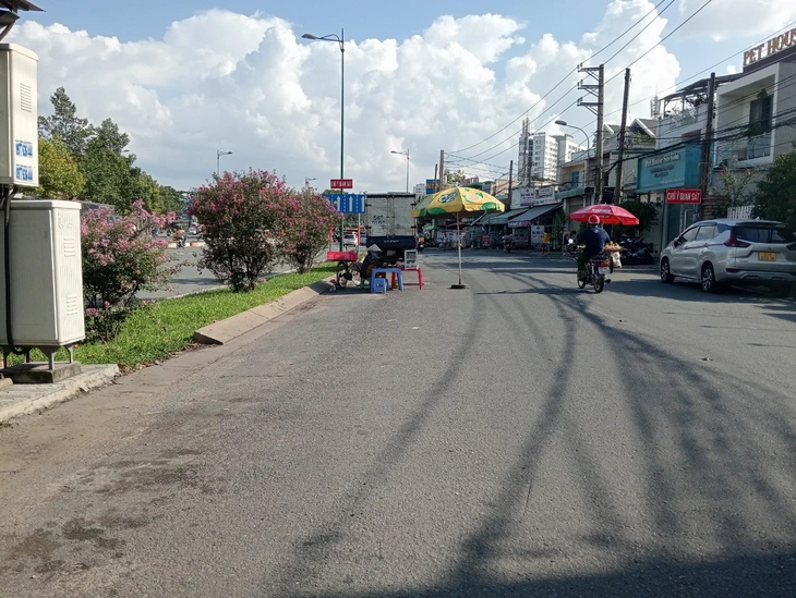Một người bán hàng đặt cây dù án ngữ giữa đường - Ảnh: ĐỊNH DƯƠNG
