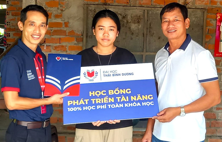 Đại diện Trường đại học Thái Bình Dương trao học bổng toàn khóa cho em Lê Vũ Hoài Trinh - Ảnh: BẢO NGUYÊN